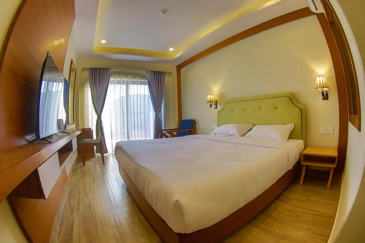 Spacious deluxe king room with wooden floors and full-height curtains